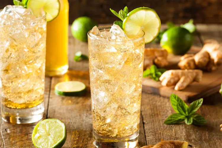 A Ginger Beer cocktail in a glass filled with ice and garnished with a lime and mint